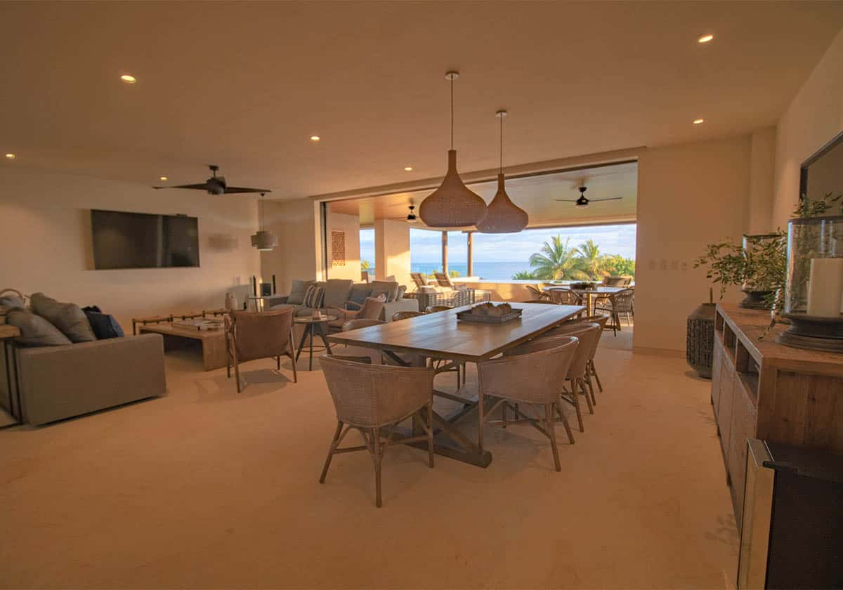 Front view of a living area with a private pool and seaside view on a beautiful sunset evening