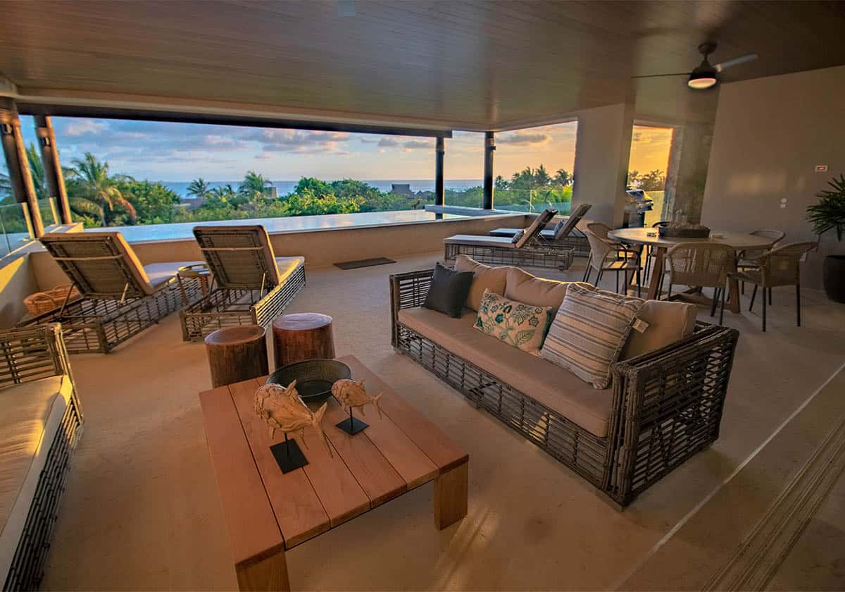 Front view of a living area with a private pool and seaside view on a beautiful sunset evening